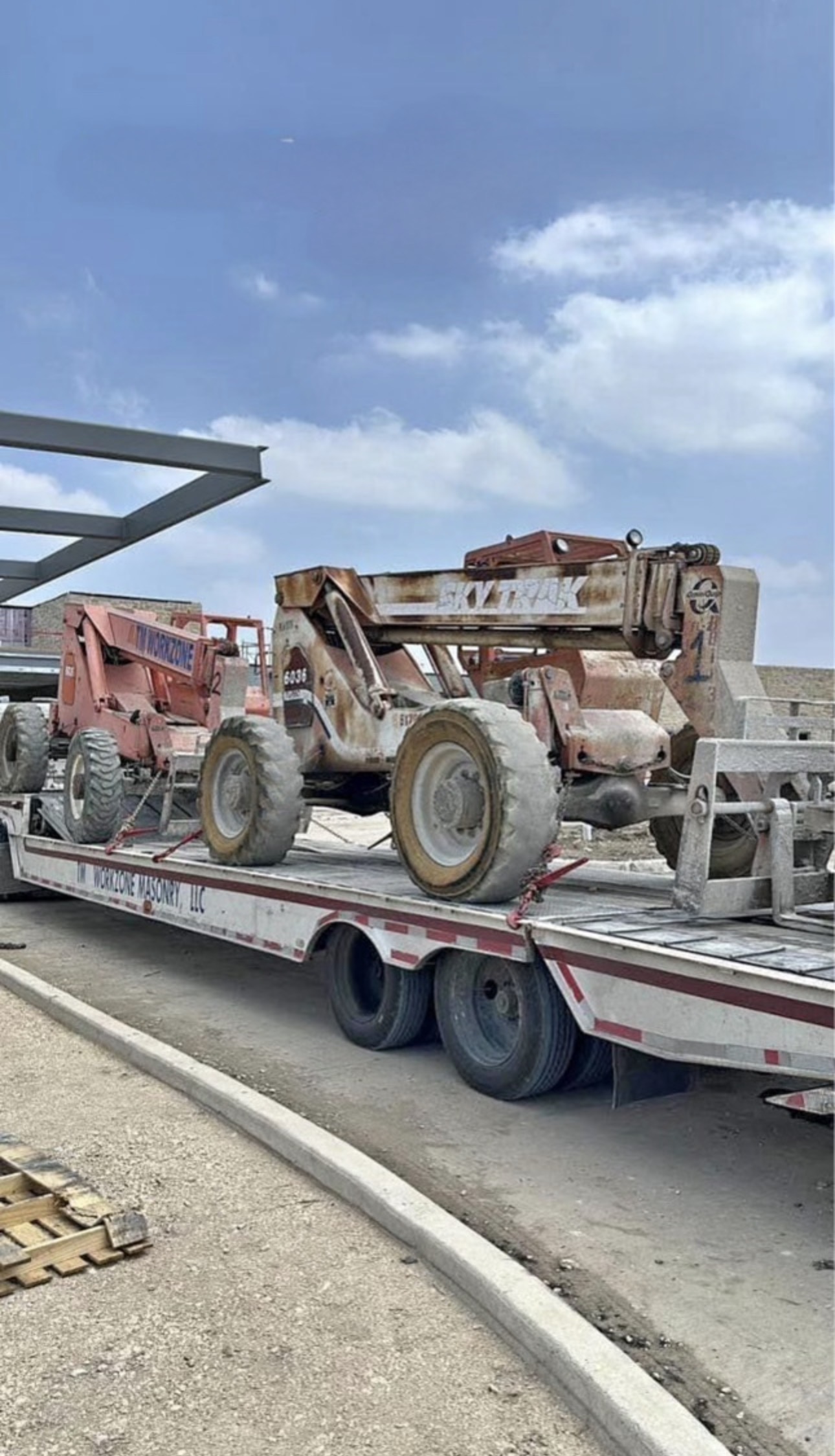 Two older telehandlers loaded on a flatbed trailer for fleet reduction or equipment liquidation