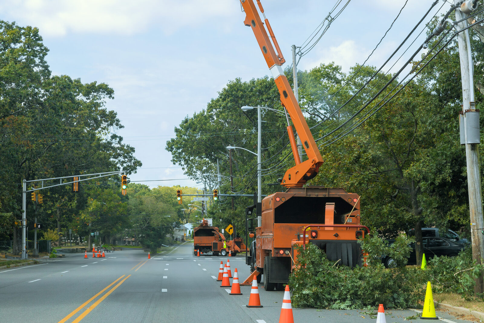 Tree cutting boom truck parked along a suburban road with cones in place